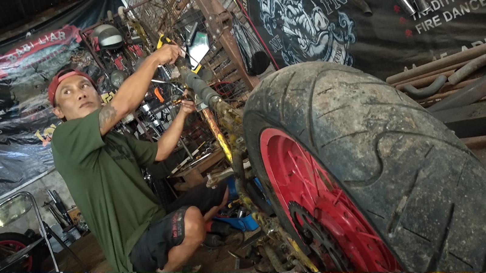 PERBAIKI MOTOR COSTUM: Suro, tengah asyik memperbaiki motor costum jenis Chopper, milik anggotanya, di Kandang Babi Liar, Desa Duman, Kecamatan Lingsar, Lombok Barat. (HARLI/LOMBOK POST)