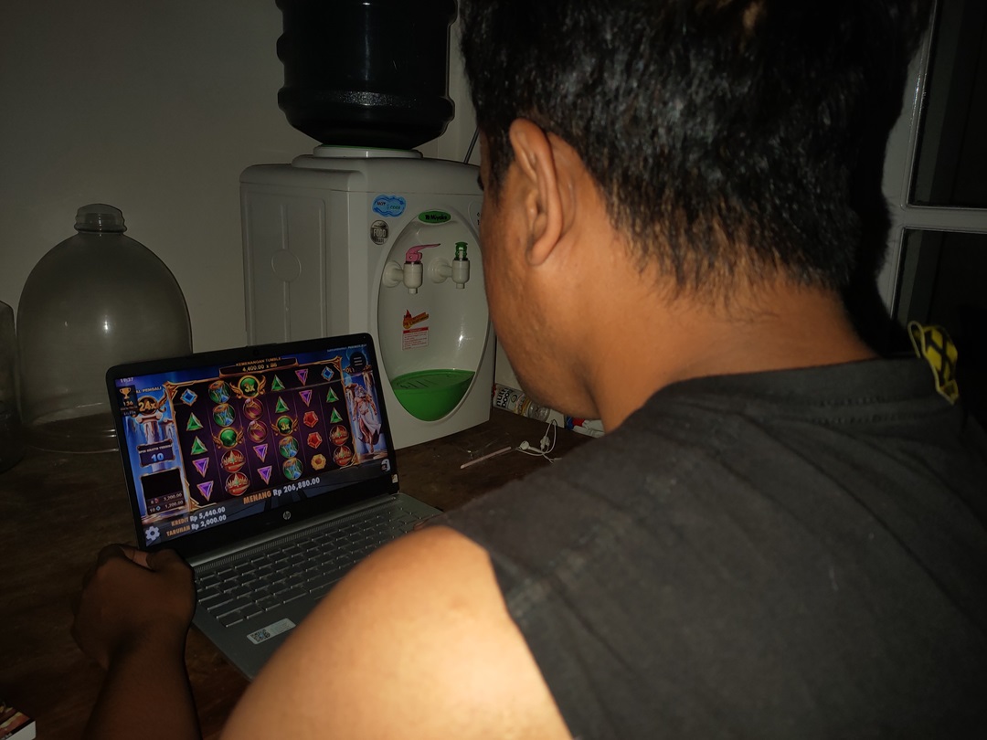 HARUS DIHINDARI: Seorang warga melihat cara orang bermain judi slot melalui YouTube di laptopnya. (ILUSTRASI LOMBOK POST)