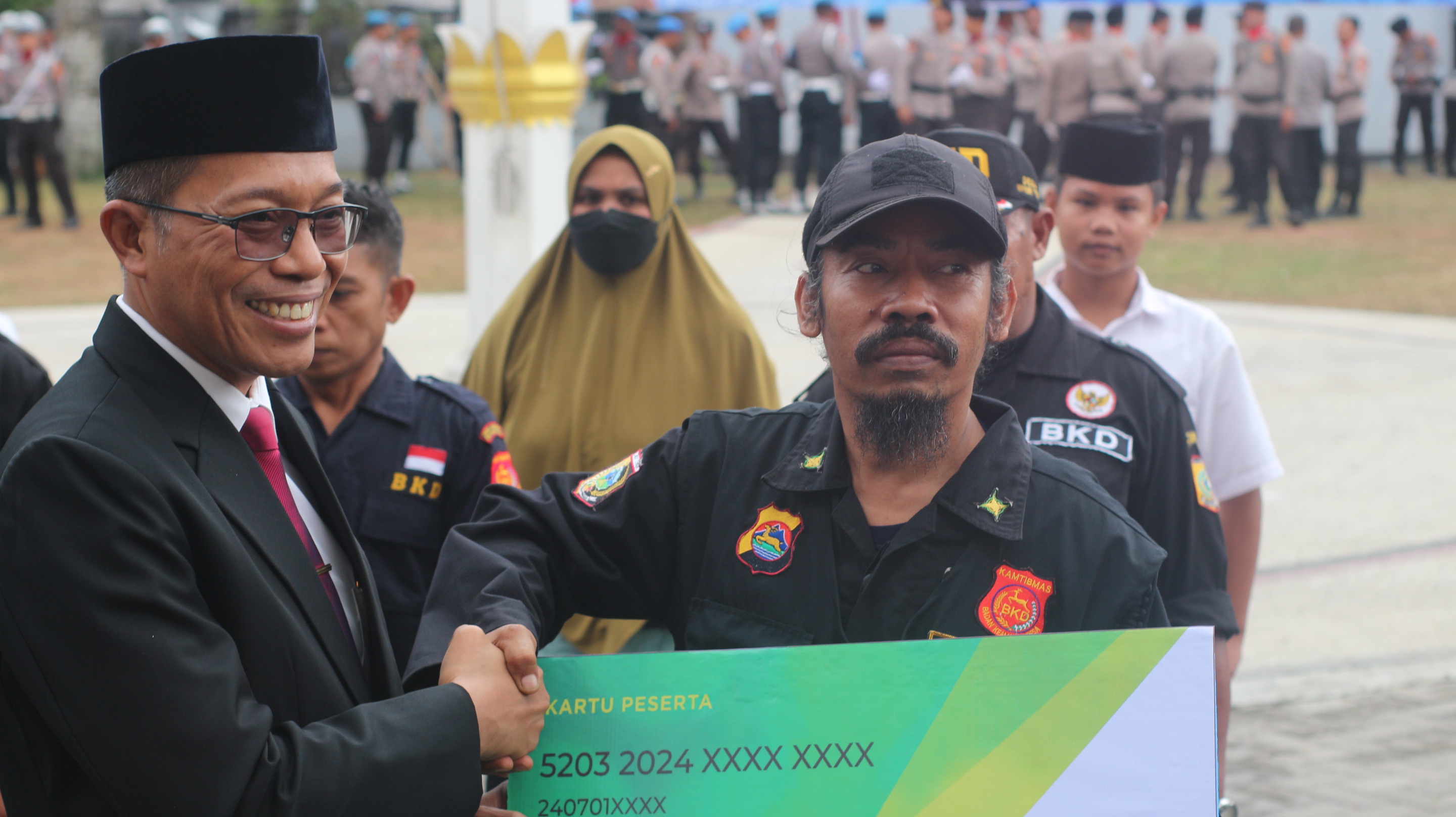 SERAHKAN: PJ Bupati Lotim H M Juaini Taofik saat menyerahkan kartu BPJS Ketenagakerjaan secara simbolis kepada Badan Keamanan Desa (BKD) yang telah didaftarkan. (SUPARDI/LOMBOK POST)