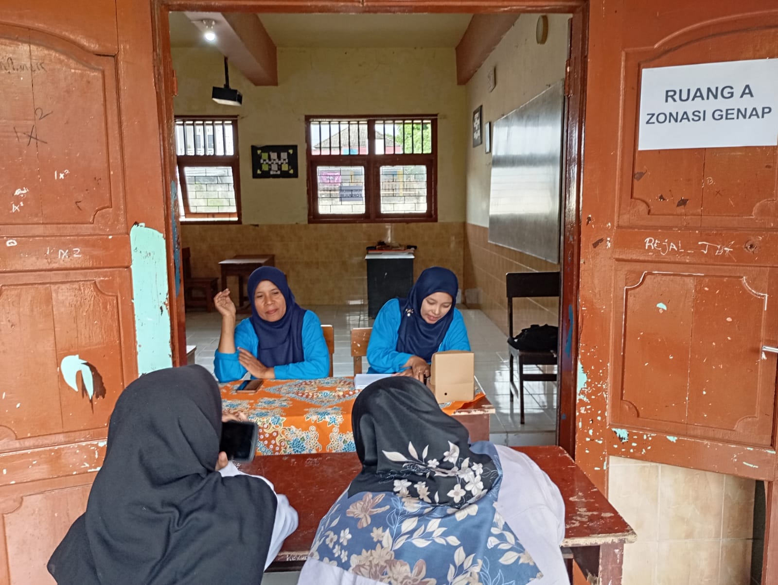 MELAYANI PENDAFTAR: Dua orang panitia PPDB SMPN 4 Mataram melayani peserta yang mendaftar di sekolah setempat, kemarin (1/7). (ROJAI/LOMBOK POST)