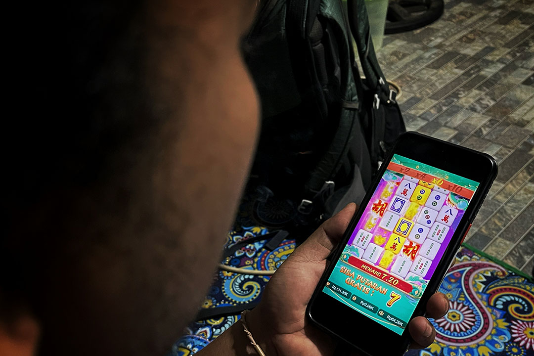ILUSTRASI: Seorang warga tengah melihat aplikasi judi online. (IVAN/LOMBOK POST)