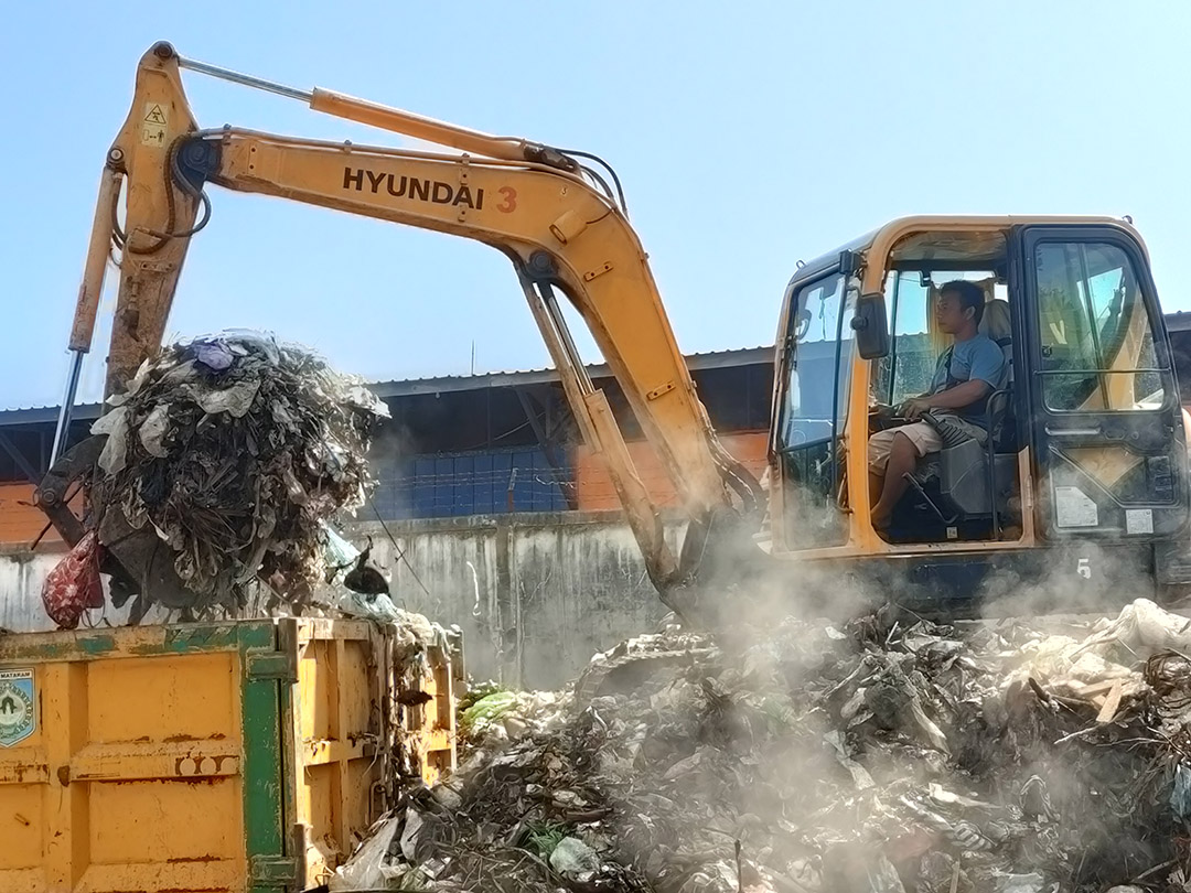 URUS SAMPAH: Operator alat berat Dinas Lingkungan Hidup Kora Mataram mengangkat sampah yang ada di TPST Sandubaya, kemarin. (HARLI/LOMBOK POST)