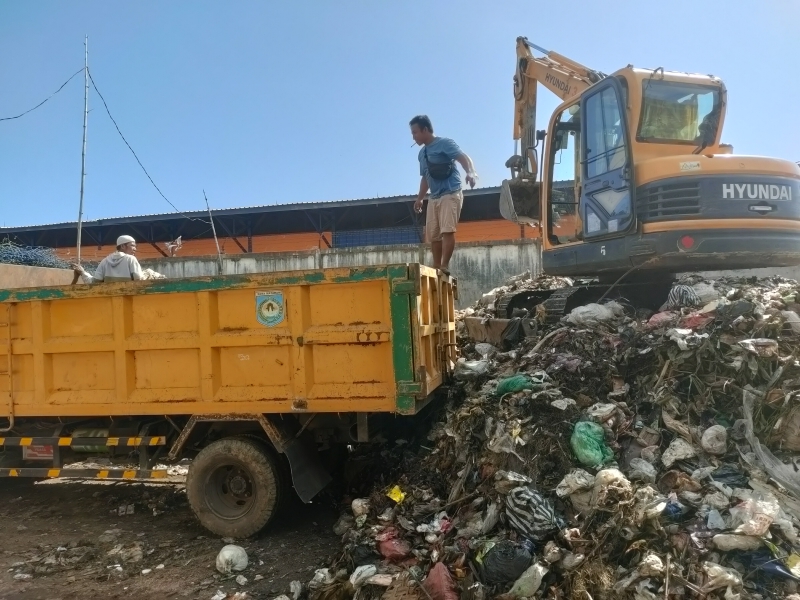 KERJA KERAS: Operator pengangkut sampah naik ke atas truck pengangkut sampah saat hendak mengangkut sampah yang bertumpuk di TPST Sandubaya, Minggu (7/7). (Harli/Lombok Post)