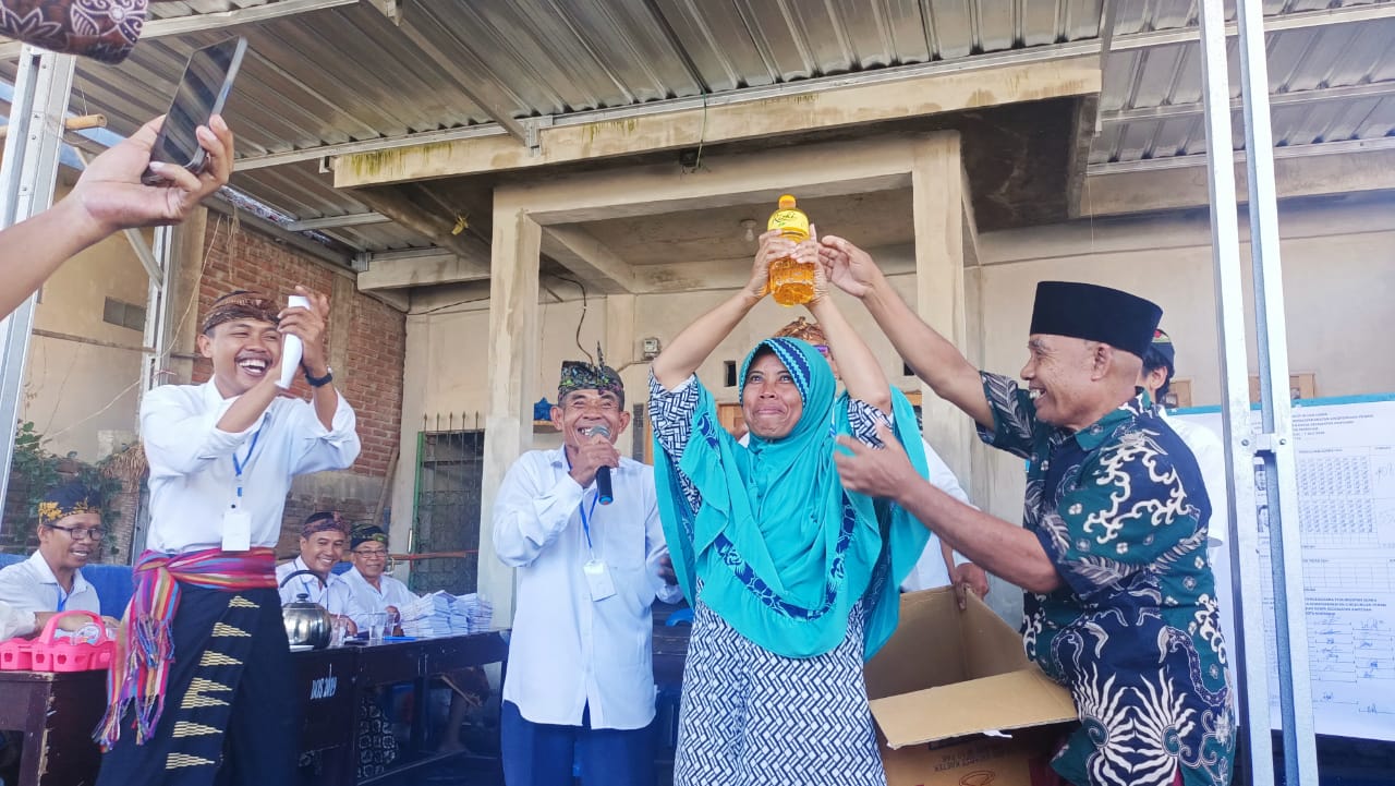 HADIAH PILKALING : Suyatni, mengangkat sebotol Minyak Goreng sebagai salah satu hadiah undian bahan pokok dalam pemilihan Kepala Lingkungan Penan Pejarakan Karya Ampenan, Minggu (7/7)