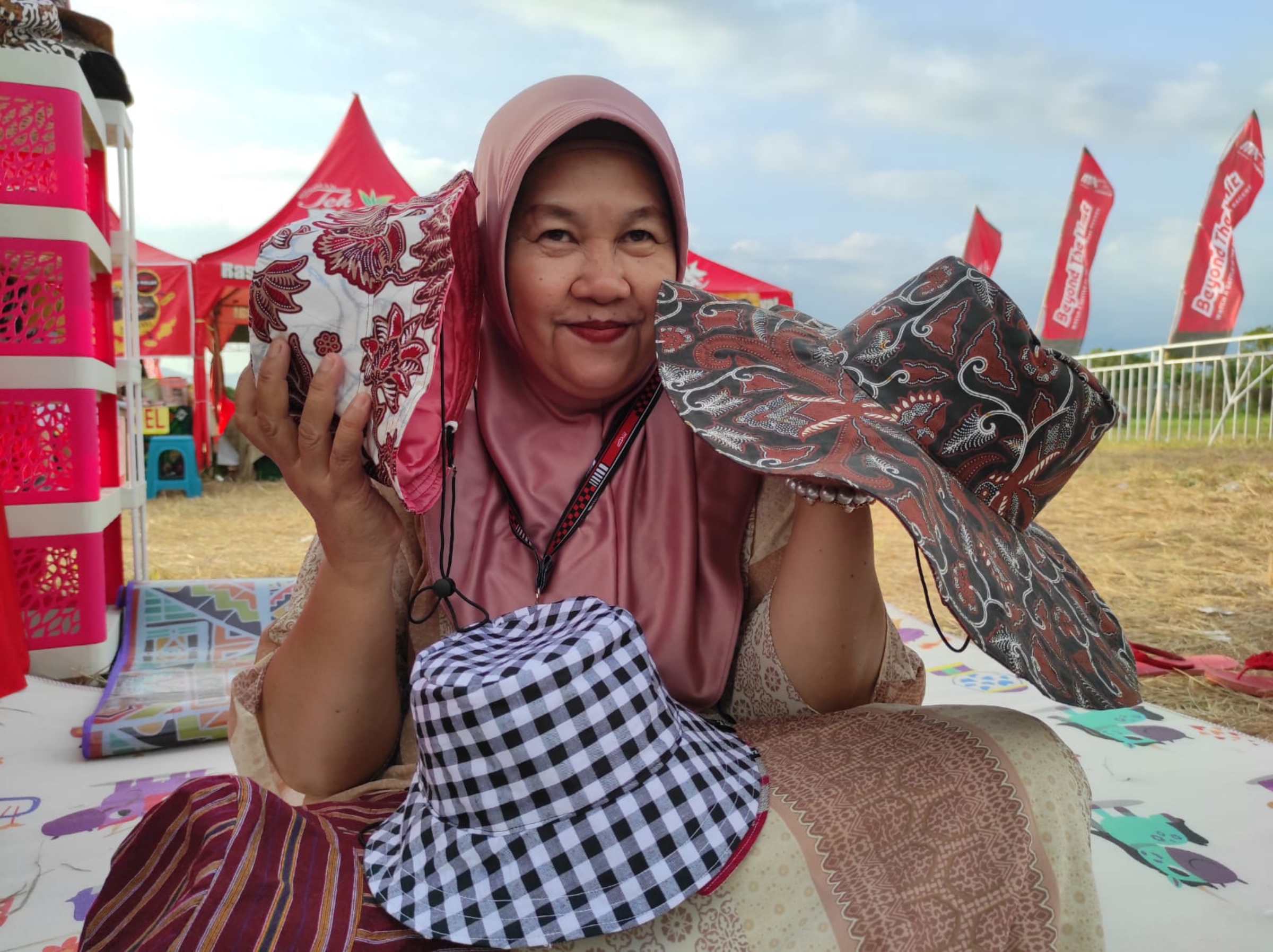 MENJANJIKAN: Owner Rumah Kreatif Bank Sampah Linsi Husni Hari menunjukkan topi hasil daur ulang sampah sisa kain yang dijual dalam kegiatan MXGP di Sirkuit Selaparang, Kota Mataram. (FERIAL/LOMBOK POS