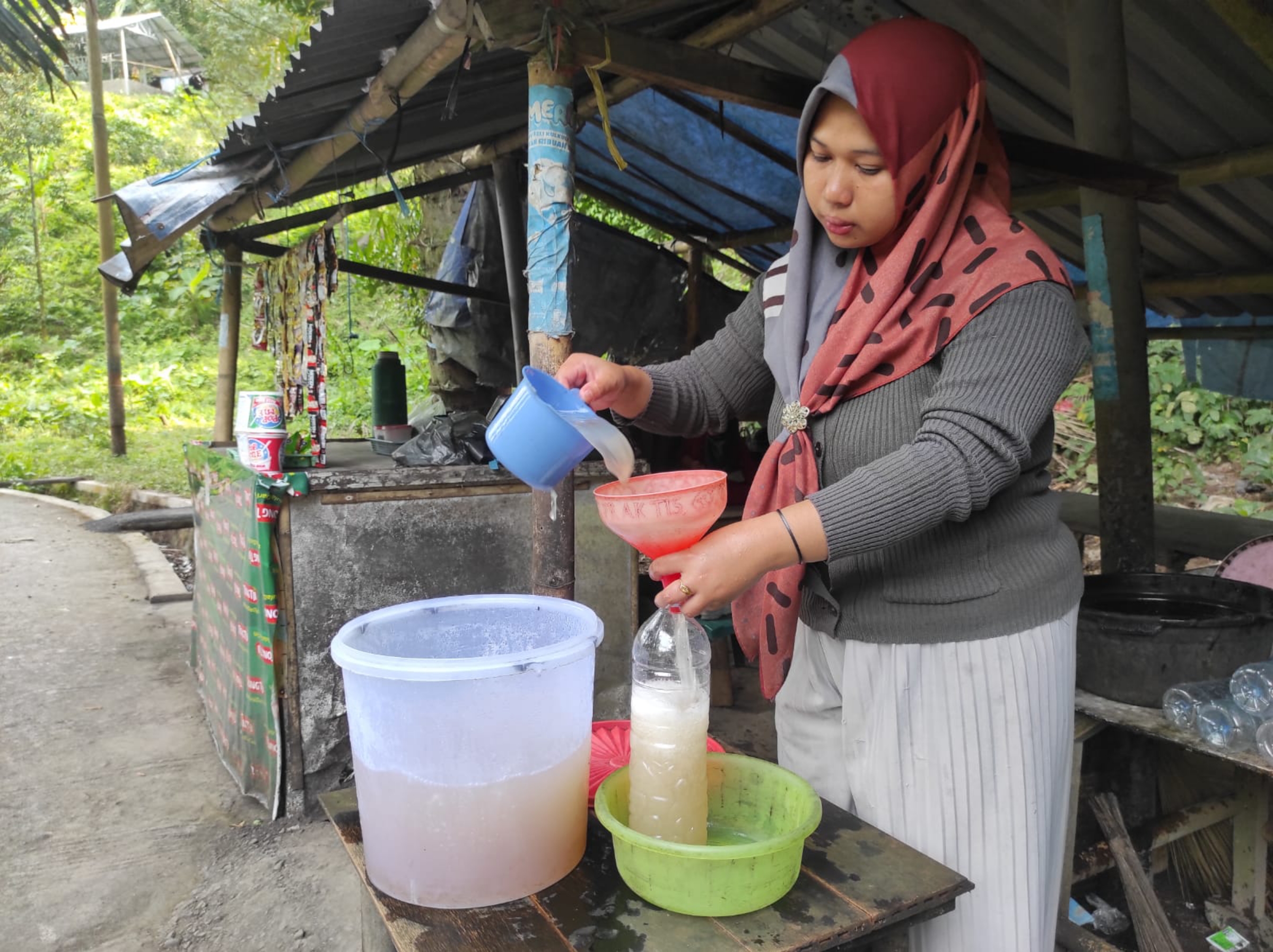 CUAN BESAR: Nurul Hikmah tengah memasukkan air tuak manis dalam botol ukuran 1,5 liter yang menjadi pesanan pembeli, belum lama ini.(FERIAL/LOMBOK POST)