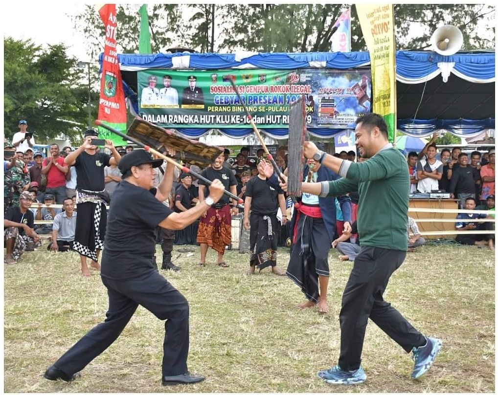 HIBURAN: Bupati Lombok Utara Djohan Sjamsu (kiri) bersama Wakil Bupati Lombok Utara Danny Karter Febrianto Ridawan (kanan) mencoba peresean dalam sosialisasi pemberantas rokok ilegal. (Ist)