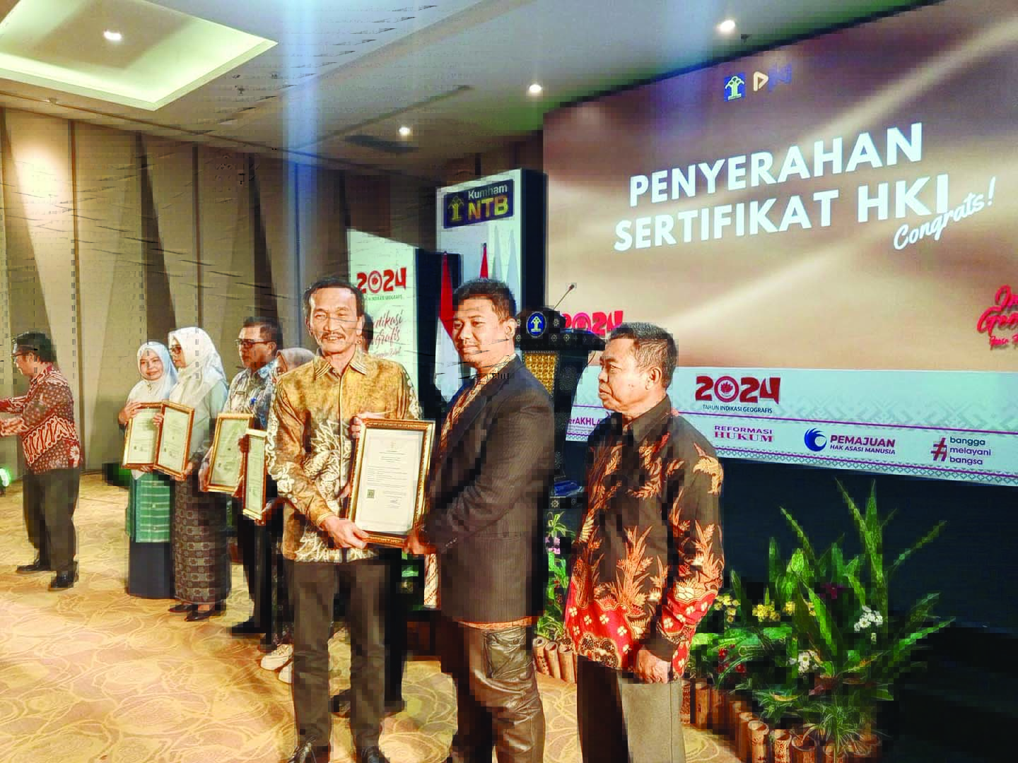 SENYUM: Ahmad Murad saat menerima KIK Ayam Taliwang yang diserahkan Direktur Hak Citpa dan Desain Industri, Kemenkumham RI Ignatius MT Silalahi, kemarin (25/7).  (ZAD/LOMBOK POST)