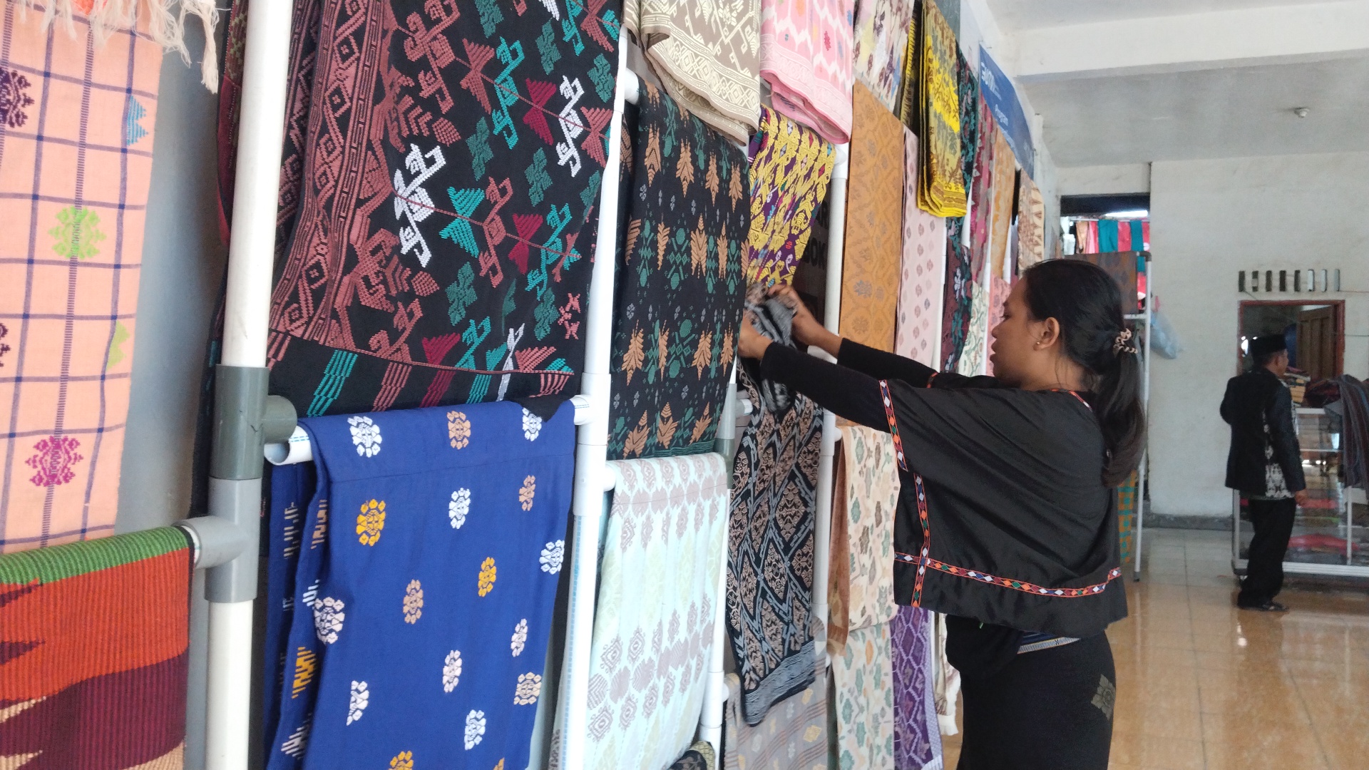 SEMOGA DILIBATKAN: Seorang pengunjung memfoto motif kain tenun khas Sukarara di salah satu artshop Desa Sukarara, Kecamatan Jonggat, Loteng, Minggu (27/7). (FOTO: Dewi/Lombok Post)