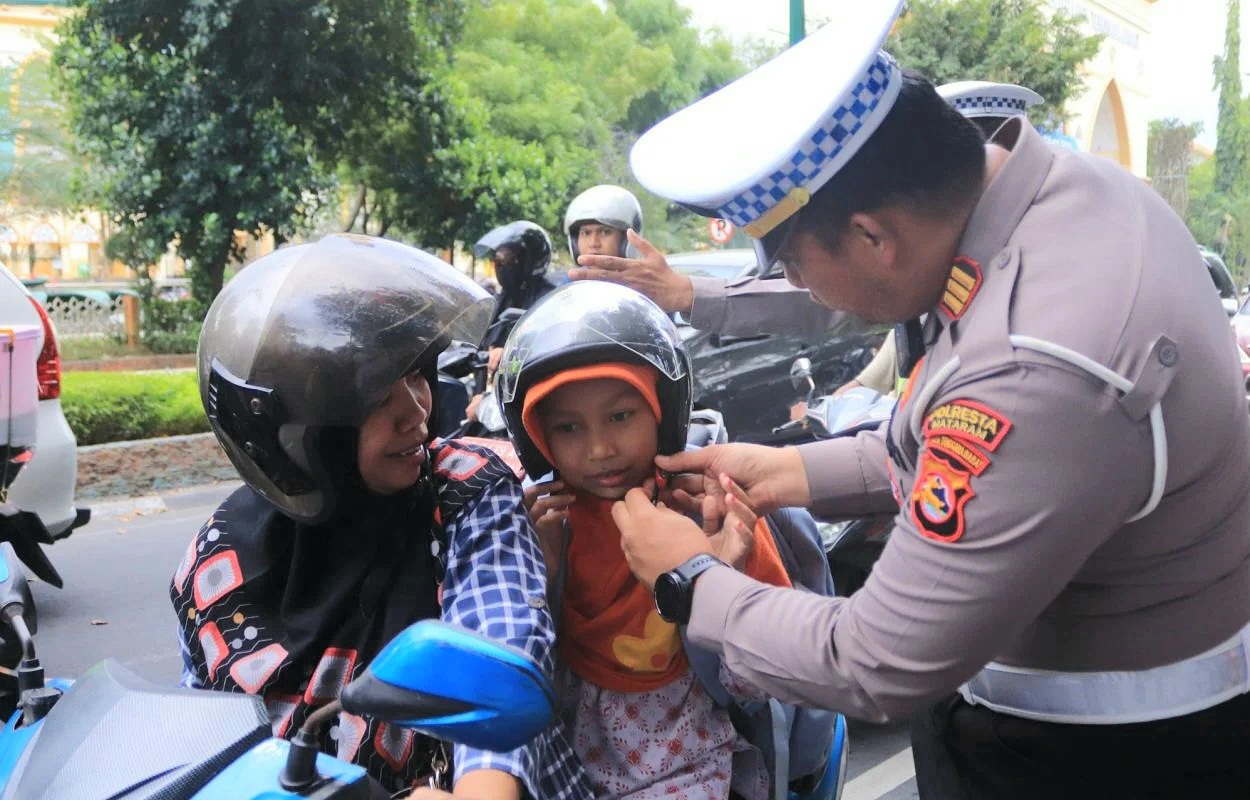 BERI EDUKASI: Kasatlantas Polresta Mataram AKP Yozana Fajri Sidik memasang helm kepada salah satu bocah yang dibonceng orang tuanya saat Operasi Patuh Rinjani. (DOK SATLANTAS POLRESTA MATARAM)