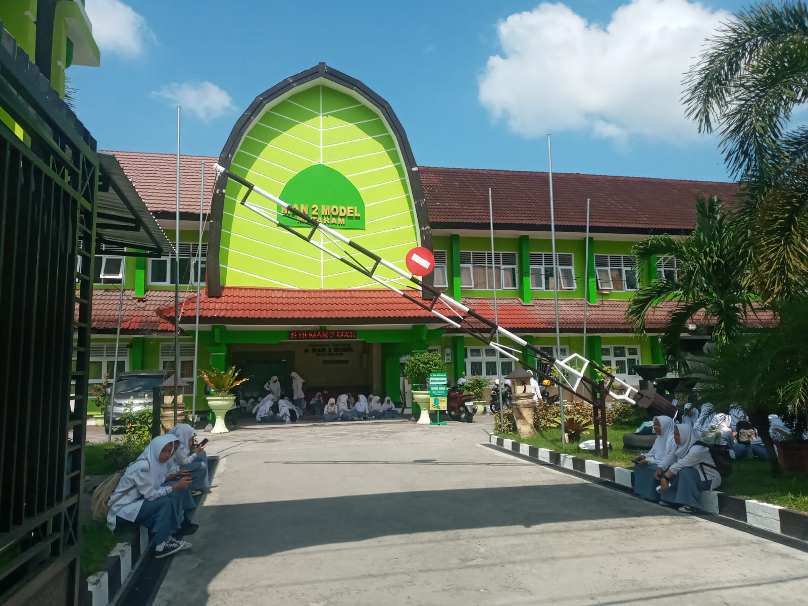 MENDUNIA: Siswa MAN 2 Mataram duduk di depan pintu masuk madrasah setempat, belum lama ini. (Rojai/Lombok Post)