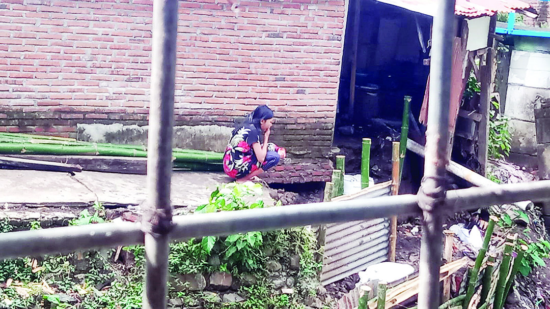 SEDIH: Seorang warga menatapi tepian rumahnya yang ambles oleh derasnya aliran air sungai di kawasan Karang Sukun, Kota Mataram, kemarin (31/7).  (ZAD/LOMBOK POST)