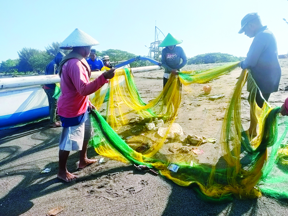 JARING IKAN: Sejumlah nelayan memisahkan ikan dan sampah yang terjaring di pinggir pantai Loang Baloq, Mataram, kemarin (12/8).  (HARLI/LOMBOK POST)