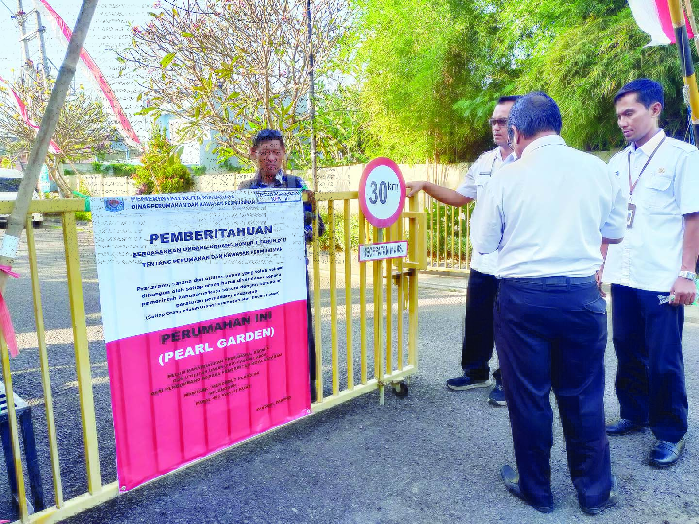 BELUM SERAHKAN PSU: Tim dari KPK menempelkan spanduk di gerbang Perumahan Pearl Garden yang belum menyerahkan PSU ke Pemkot Mataram, kemarin (14/8).(HARLI/LOMBOK POST)