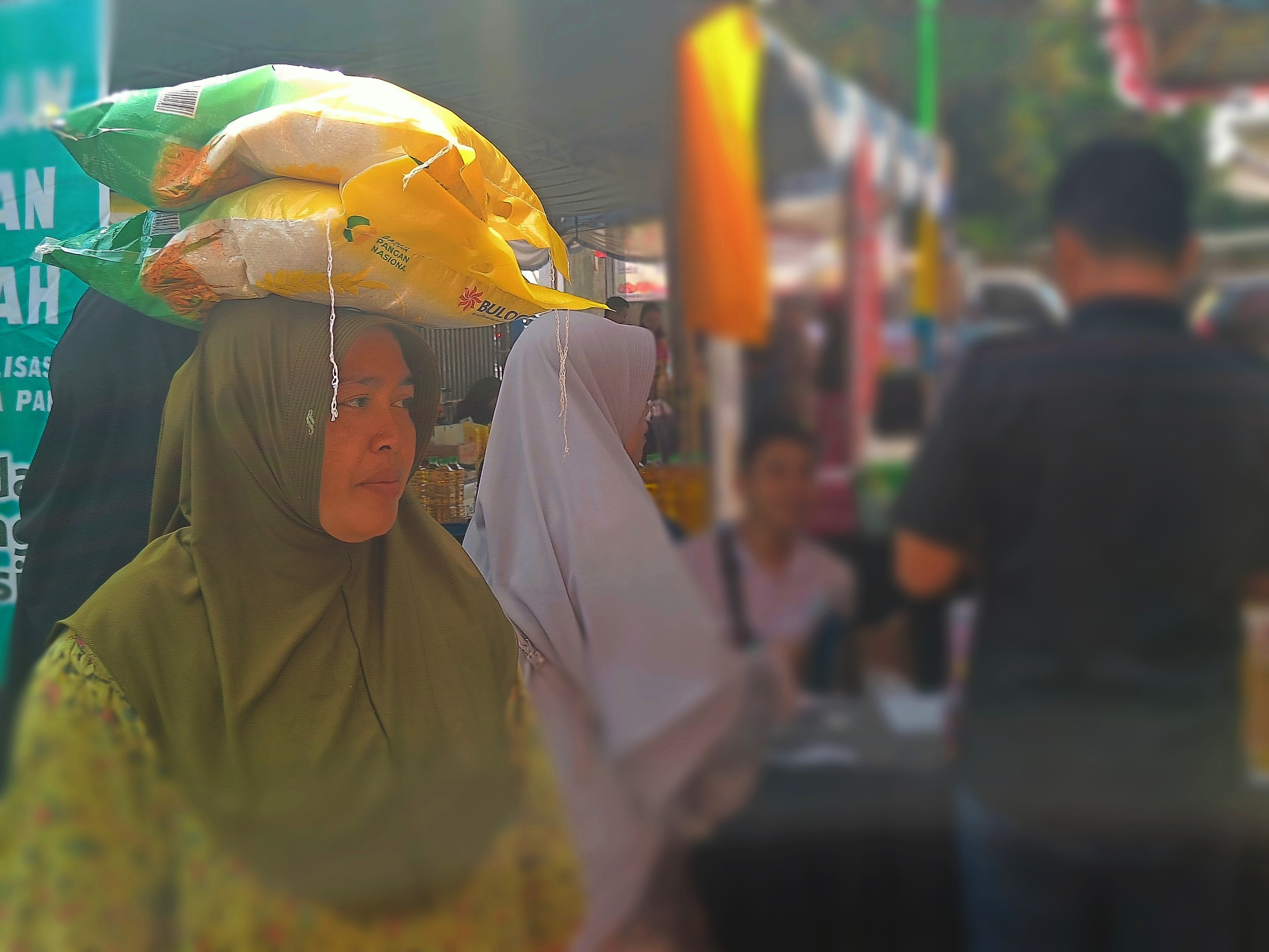 BAHAN POKOK: Seorang warga tengah menyinggi beras di atas kepalanya, kemarin  (20/8). (ZAD/LOMBOK POST)