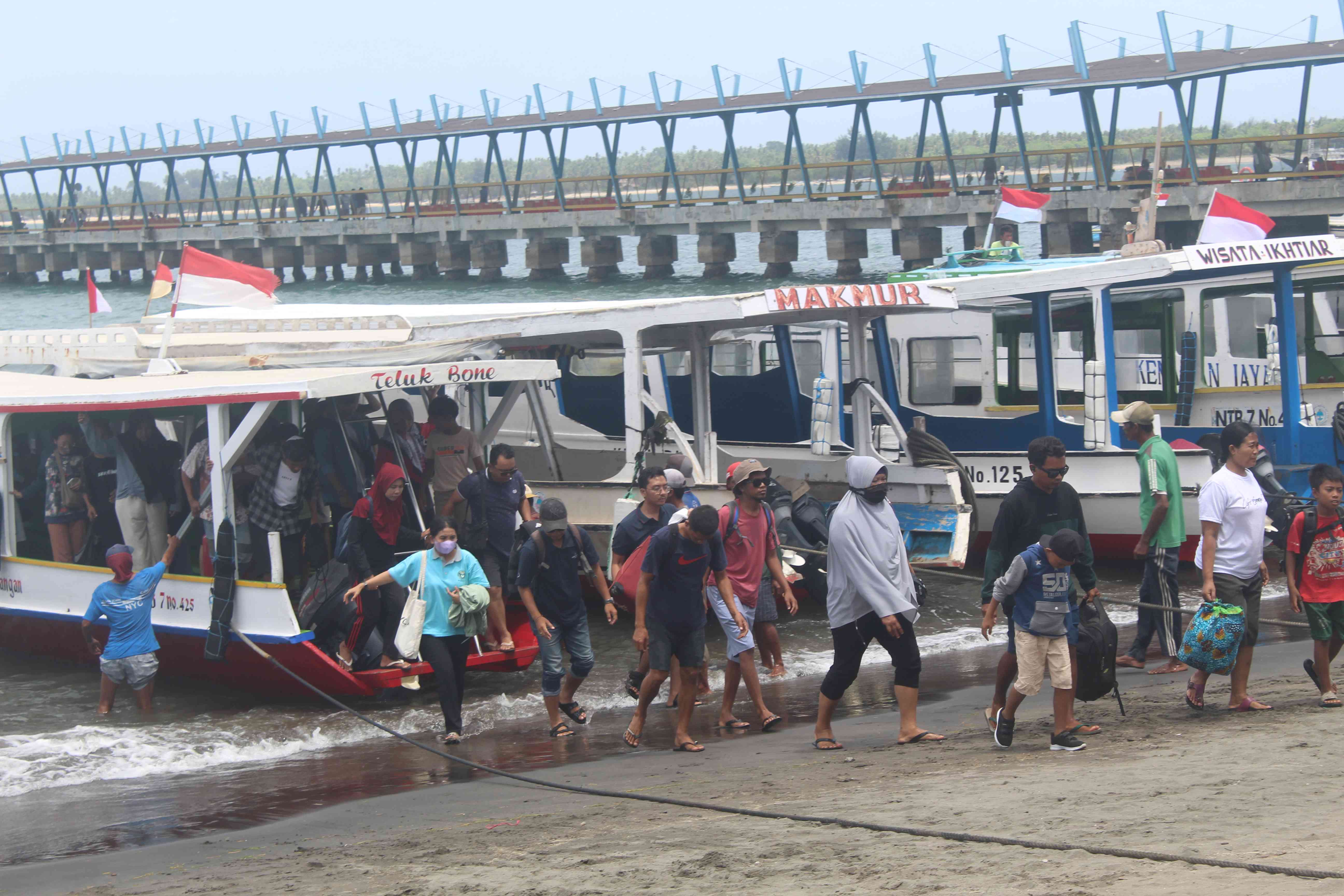 TIBA DENGAN SELAMAT: Wisatawan termasuk warga sekitar turun dengan hati-hati dari kapal yang ditumpanginya, dari Pelabuhan Gili Trawangan menuju Pelabuhan Bangsal, Lombok Utara. (YUYUN/LOMBOK POST)