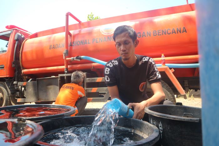 DISTRIBUSI: Petugas Badan Penanggulangan Bencana Daerah (BPBD) Lotim saat mendistribusikan air bersih kepada warga Dusun Rengga Trans, Desa Puncak Jeringo Kecamatan Suela, yang terdampak kekeringan.