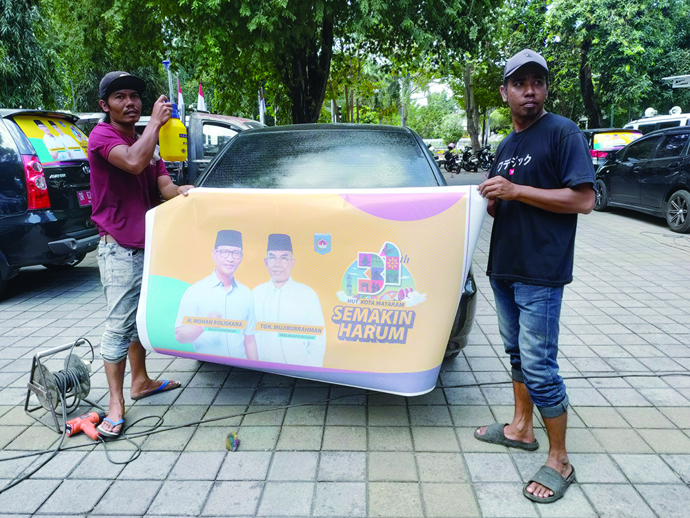 Sejumlah pegawai mencopot banner HUT Kota Mataram yang terpasang pada sejumlah kendaraan dinas, beberapa waktu lalu.