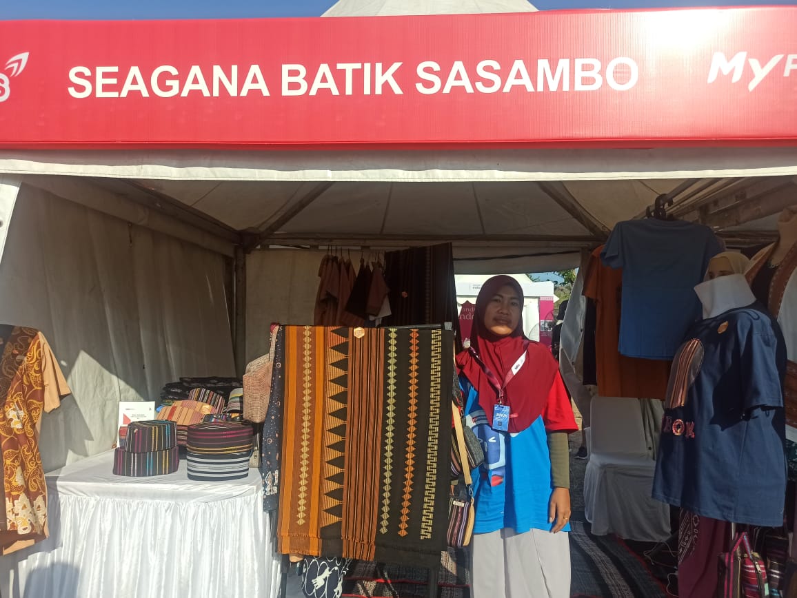 MENUNGGU PEMBELI: Saiyah menunjukkan beberapa produk yang dijual di boothnya pada kegiatan Energizing You Festival di Pertamina Mandalika International Circuit, selama tiga hari (27-29/9).