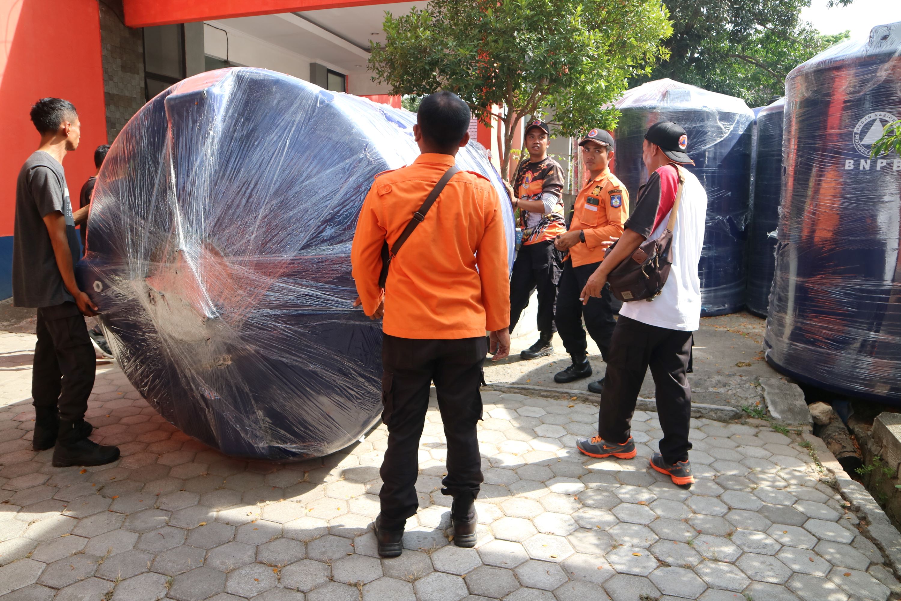 DARI PUSAT: Sejumlah petugas BPBD Loteng mengelindingkan tendon air berukuran 5.300 liter ke dalam gudang kantor BPBD Loteng, Praya, Selasa (1/10).