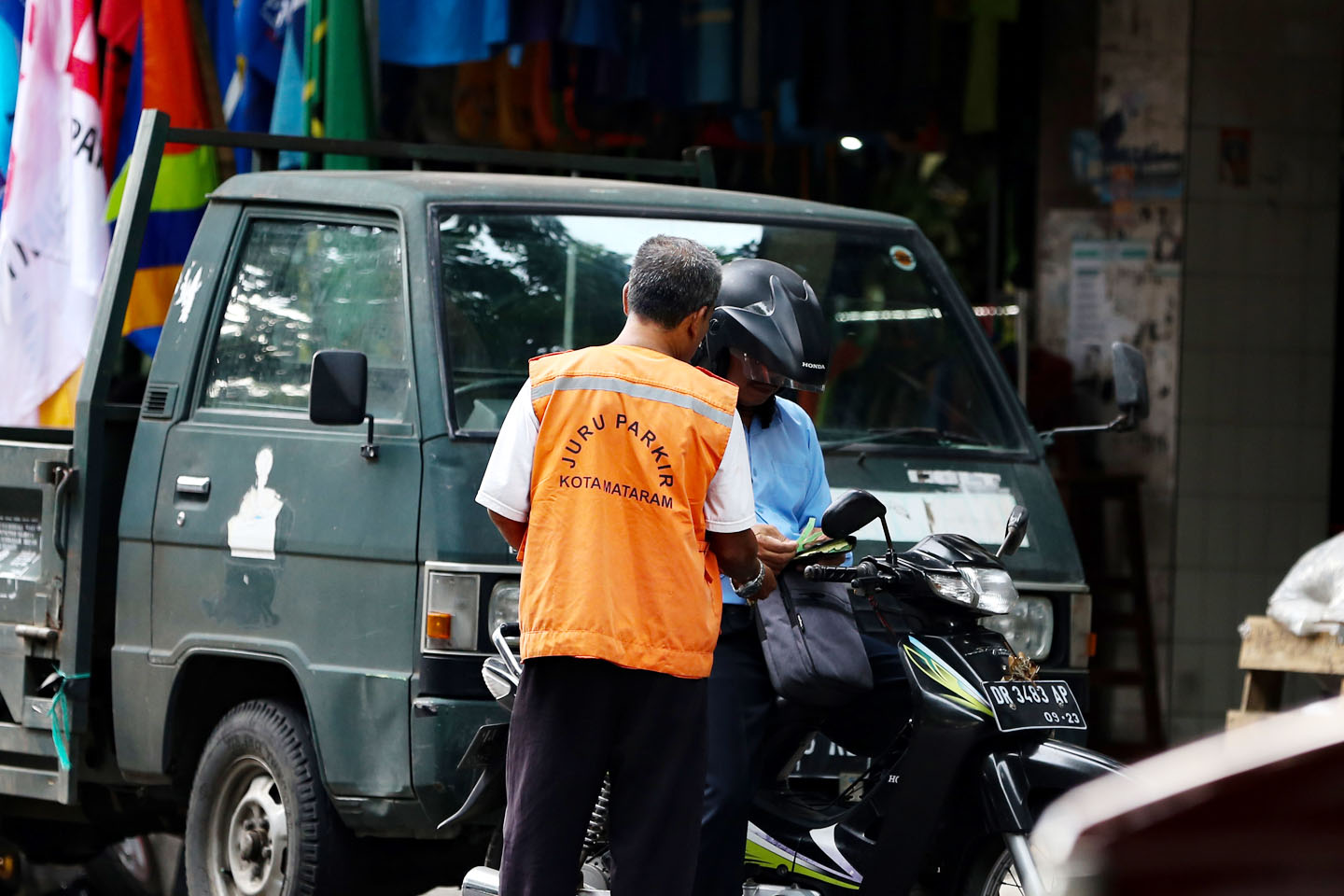 Seorang jukir meminta bayar parkir ke pengendara di salah satu jalan di Kota Mataram, belum lama ini. Parkir berlangganan baru diterapkan untuk kendaraan roda empat yang mengikuti uji KIR.