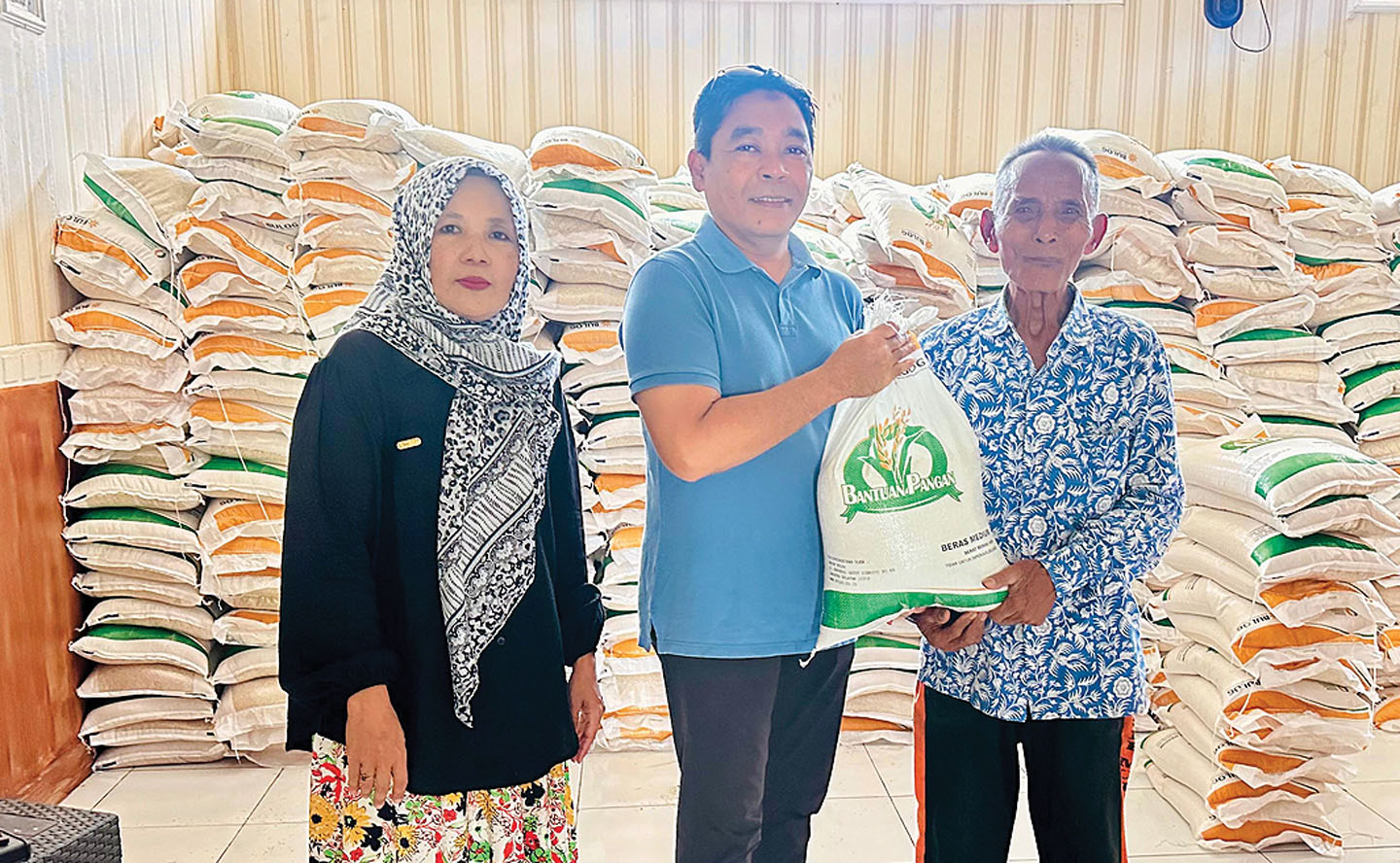 Lurah Tanjung Karang Achmad Gunawan (tengah) secara simbolis membagikan bantuan beras cadangan pangan pemerintah (CPP) ke penerima bantuan Rusdi (kanan) di aula Kelurahan Tanjung Karang.