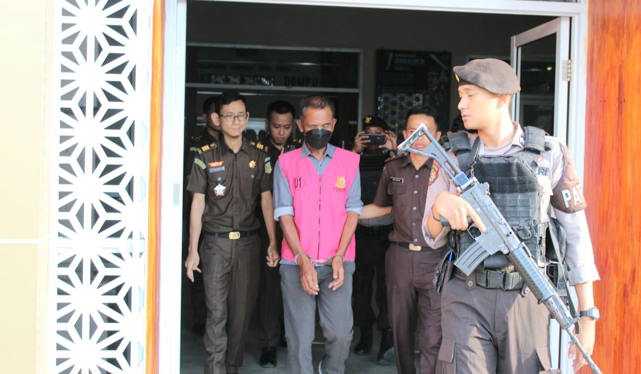 Penyidik Kejari Dompu bersama polisi bersenjata mengawal tersangka AH saat dibawa menuju mobil tahanan, Senin (21/10).