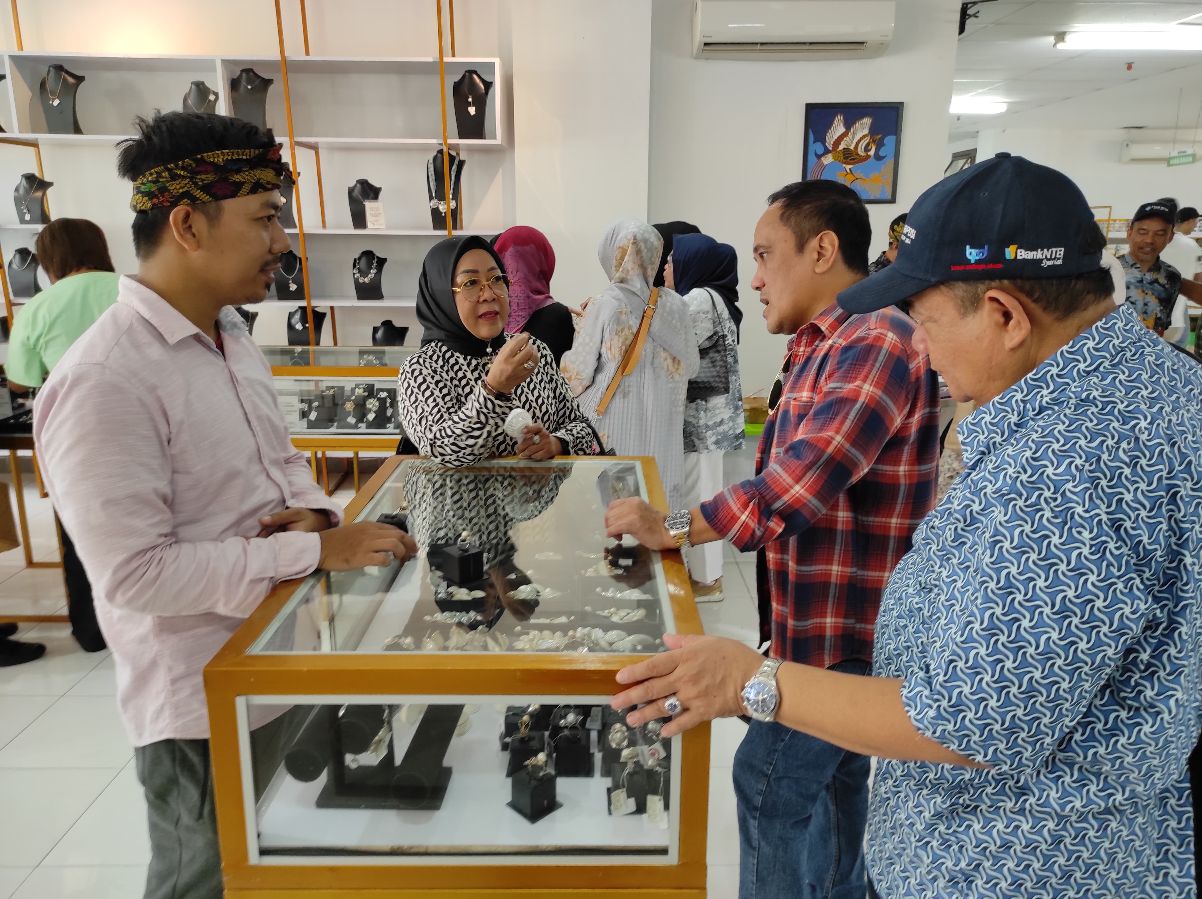 DAMPINGI TAMU: Komisaris Independen Bank NTB Syariah Hj Putu Selly Andayani (dua kiri) mendampingi tamu FKDK BPDSI wilayah timur yang mengunjungi etalase produk mutiara NTB, NTB Mall, Jumat (25/10).