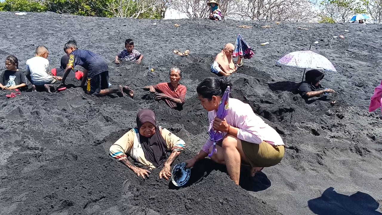 TERAPI: Seorang pengunjung asal Desa Masbagik, saat melakukan terapi kesehatan di dengan menanam sebagian anggota badan di pasir pantai Pondok Kerakat, Desa Pohgading, Kecamatan P