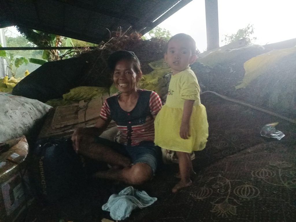 PANTANG MENYERAH: Ibu Hadiun duduk bersama anaknya yang paling kecil usai mengais sampah di TPST Sandubaya, Rabu&nbsp;(30/10).