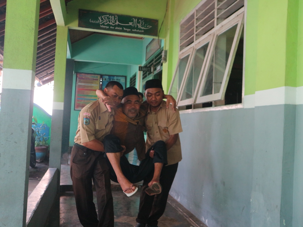SEMANGAT BEKERJA: Muhammad Fadli, seorang guru honorer disabilitas, saat dibopong oleh kepala sekolah dan keponakannya menuju kelas untuk mengajar anak muridnya Bahasa Arab di MI Muhammadiyah.