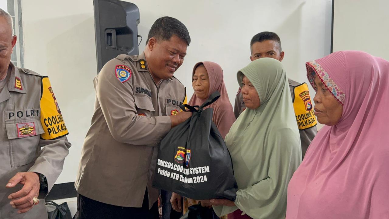 Kasubdit Bhabinkamtibmas Ditbinmas Polda NTB AKBP Nyoman Supartana memberikan bingkisan kepada masyarakat di Desa Puyung dalam kegiatan cooling system, Rabu (13/11).