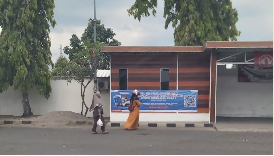 PENGUMUMAN QR CODE: Beberapa orang  melintasi pengumuman penggunaan QR Code untuk pembelian Pertalite di SPBU Selagalas, Mataram, beberapa waktu lalu. NURUL/LOMBOK POST