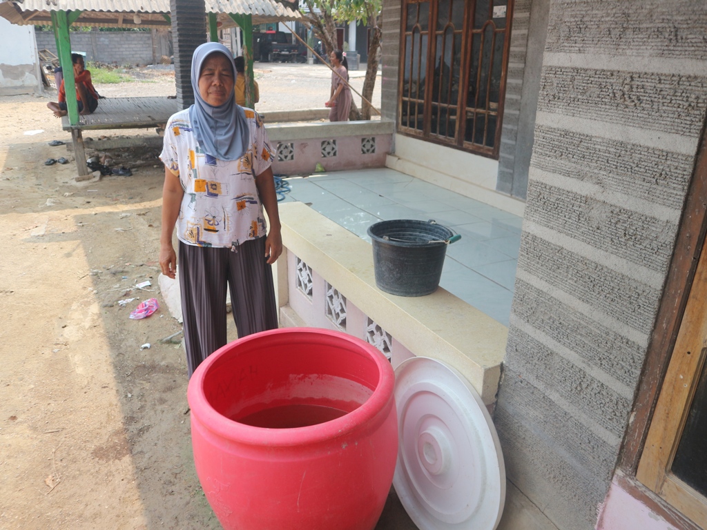 TEMPAT AIR: Sohariah, salah seorang warga Desa Sekaroh, Kecamatan Jerowaru, Lombok Timur saat memperlihatkan kondisi air hujan yang ditampung beberapa hari lalu di tong merah. SUPARDI/LOMBOK POST