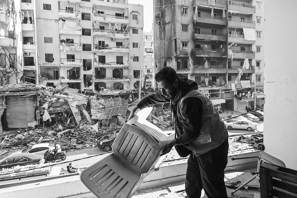 Seorang anggota staf Asosiasi Amel memilah barang-barang di kantor mereka yang rusak akibat serangan Israel di lingkungan Hay el-Sellom, pinggiran selatan Beirut, Senin (2/12).
