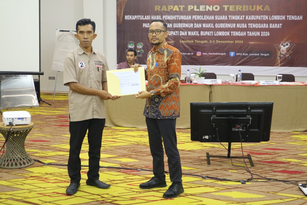 BERJALAN LANCAR: Ketua KPU Loteng Hendri Harliawan secara simbolis menyerahkan hasil rekapitulasi hasil perhitungan perolehan suara Pilkada Loteng 2024 pada saksi paslon Pathul-Nursiah di Loteng.
