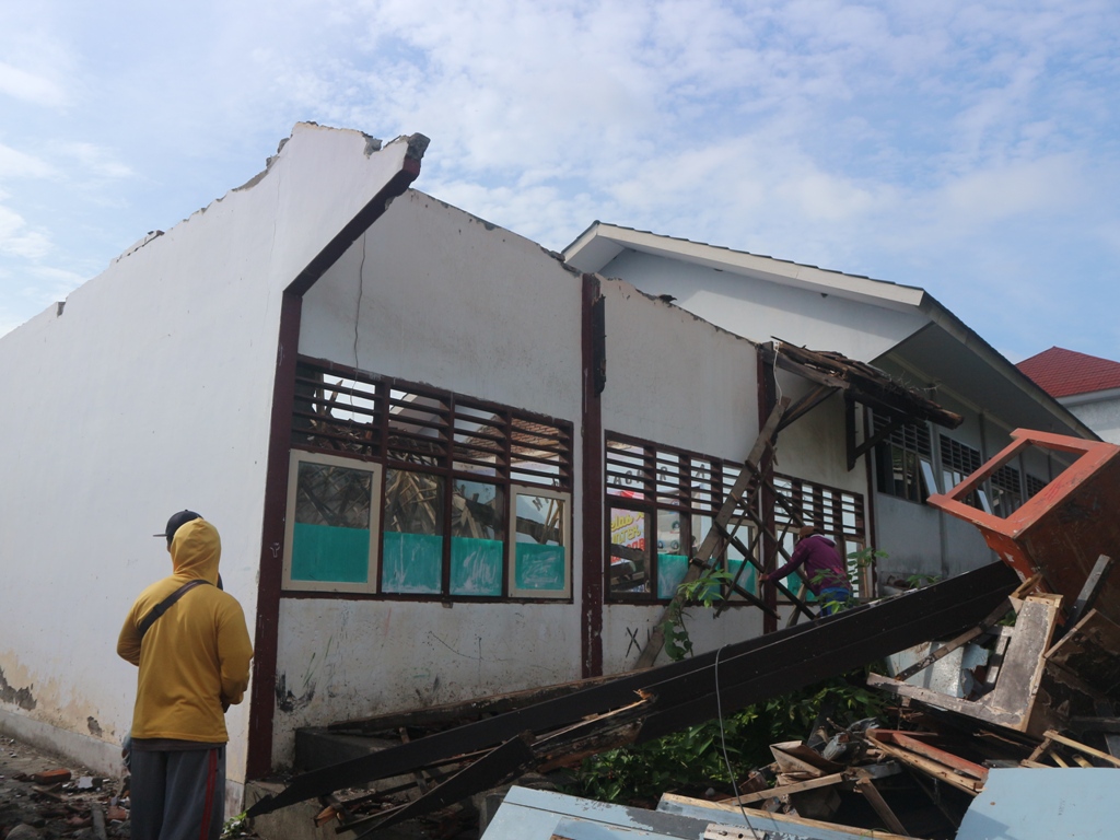 AMBRUK: Serang tukang sedang membersihkan material kayu bekas atap bangunan SMAN 1 Wanasaba yang ambruk diterjang angin, Sabtu (7/12).
