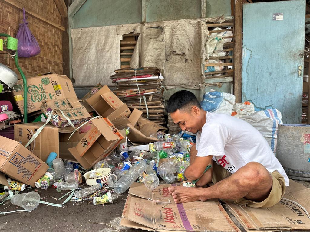BERSIHKAN: Penyandang disabilitasSupaedi, asal Dusun, Montong Meong, Desa Labuhan Haji, Kecamatan Labuhan Haji, saat membersihkan botol-botol plastik bekas di rumahnya yang dikumpulkan.