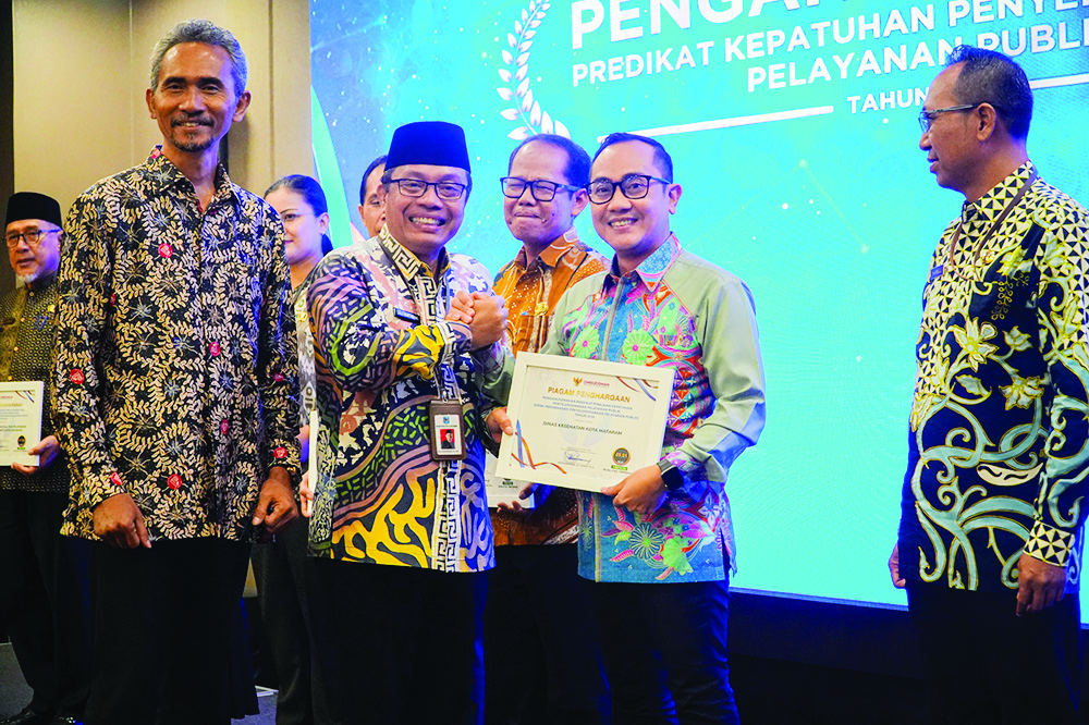 SENYUM: Asisten 1 Setda Kota Mataram Lalu Martawang menyerahkan penghargaan dari Ombudman kepada Kepala Dinas Kesehatan Kota Mataram dr H Emirald Isfihan, Jumat (6/12).