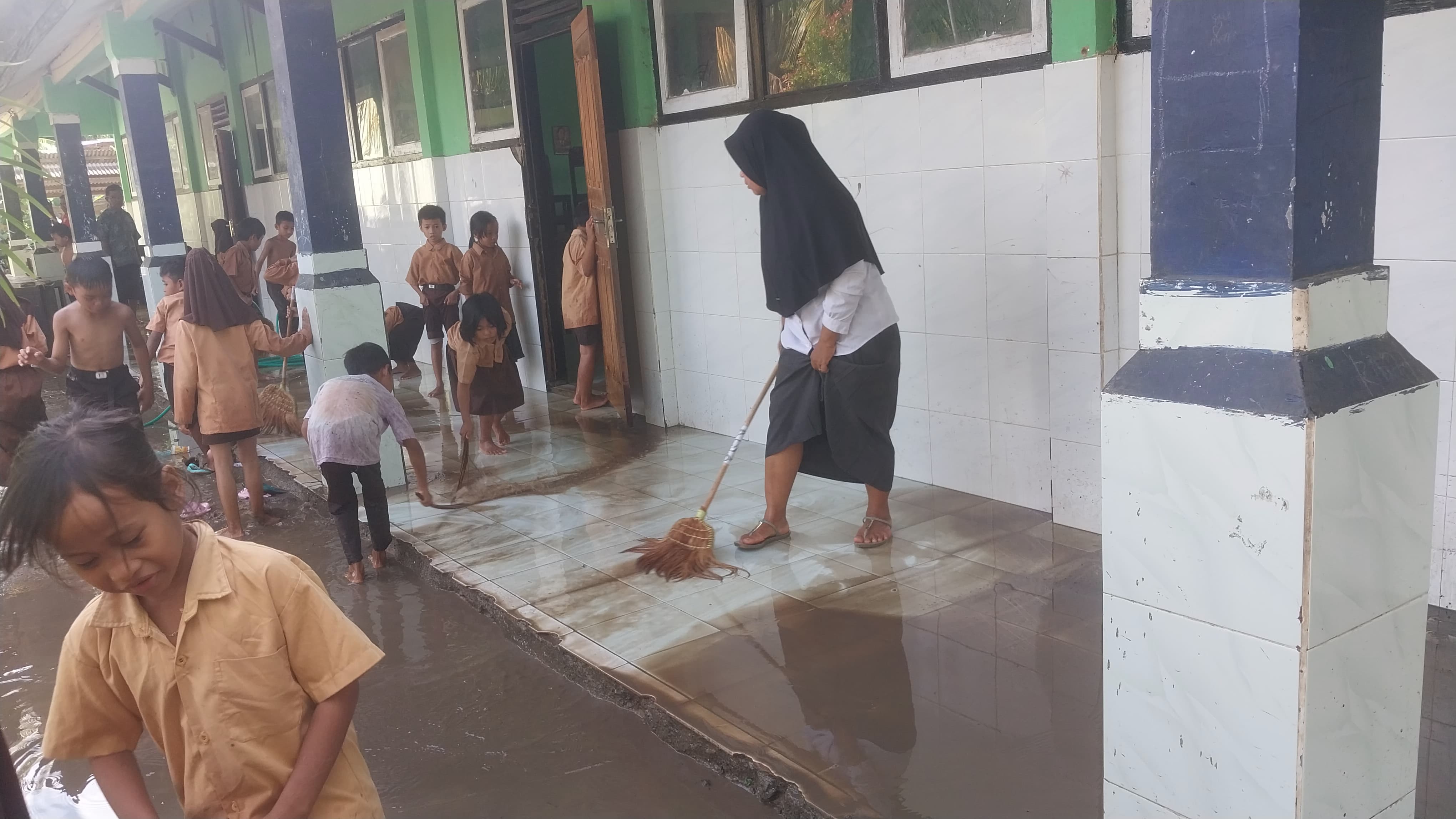 SUKACITA: Para murid penuh semangat membersihkan ruang-ruang kelas setelah terendam banjir dan menyisakan genangan lumpur di SDN Pasung, Dusun Pasung Lauk, Desa Bangket Parak.
