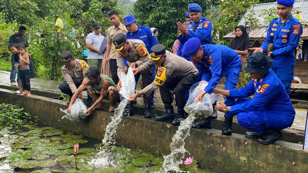 SOSIAL: Personel Polres Lombok Utara menebar ribuan benih ikan di Dusun Kerujuk, Desa Menggala, Kecamatan Pemenang, Kamis (12/12).