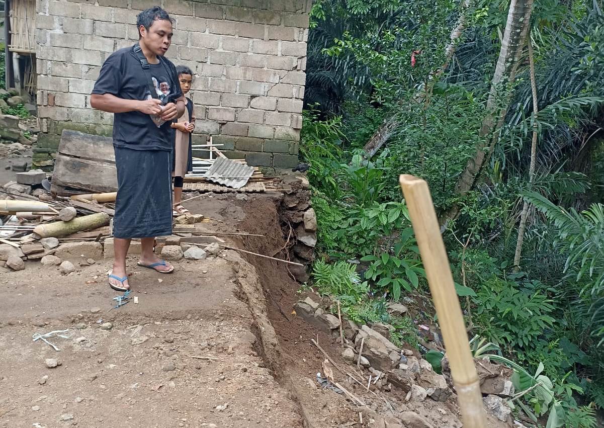 TANAH LONGSOR: Masri melihat bekas puing-puing rumahnya yang tergerus tanah longsor di Dusun Duduk Atas, Desa Batulayar Barat, Kecamatan Batulayar, Rabu (11/12).