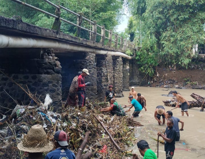 TERBAWA BANJIR: Masyarakat bersama anggota TNI berjibaku membersihkan sampah yang menyumbat jembatan akibat terbawa arus air sungai usai hujan di Dusun Benjor, Desa Penujak, Loteng.