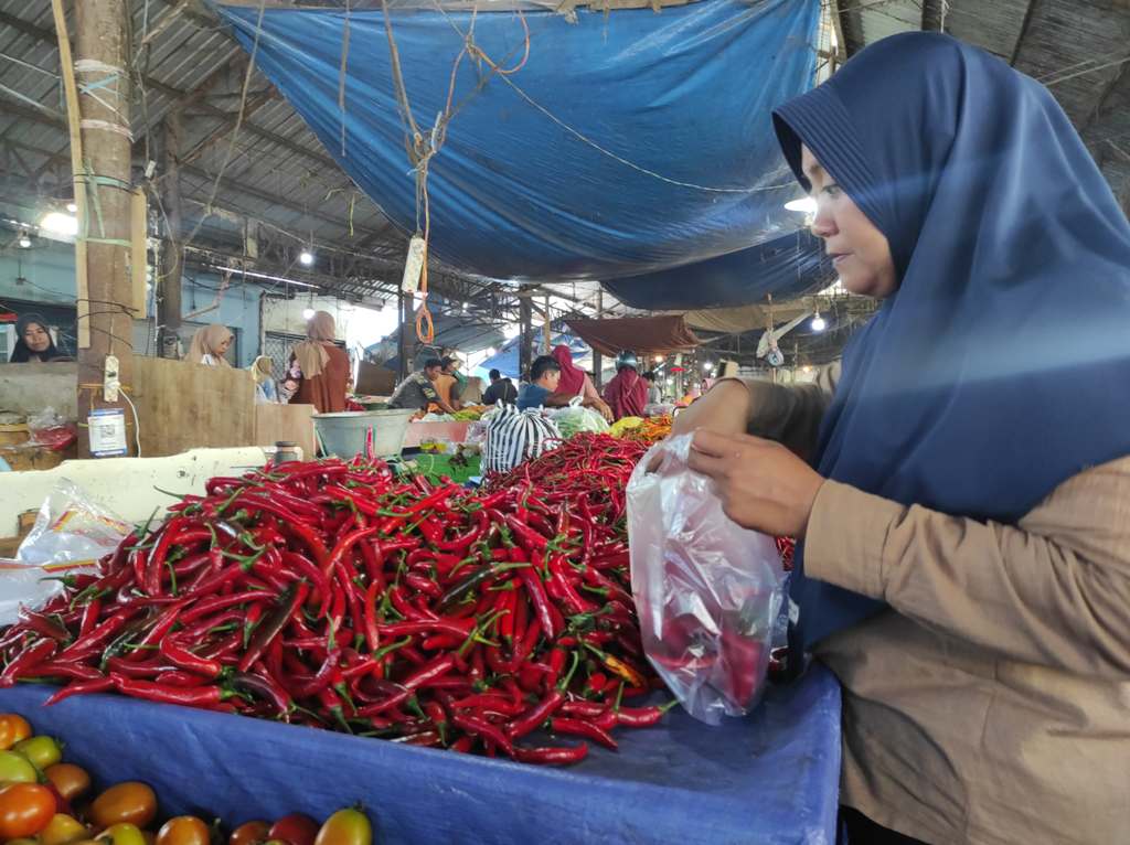 MEROKET: Salah seorang warga Kota Mataram membeli cabai merah besar di Pasar Mandalika, Senin (23/12).
