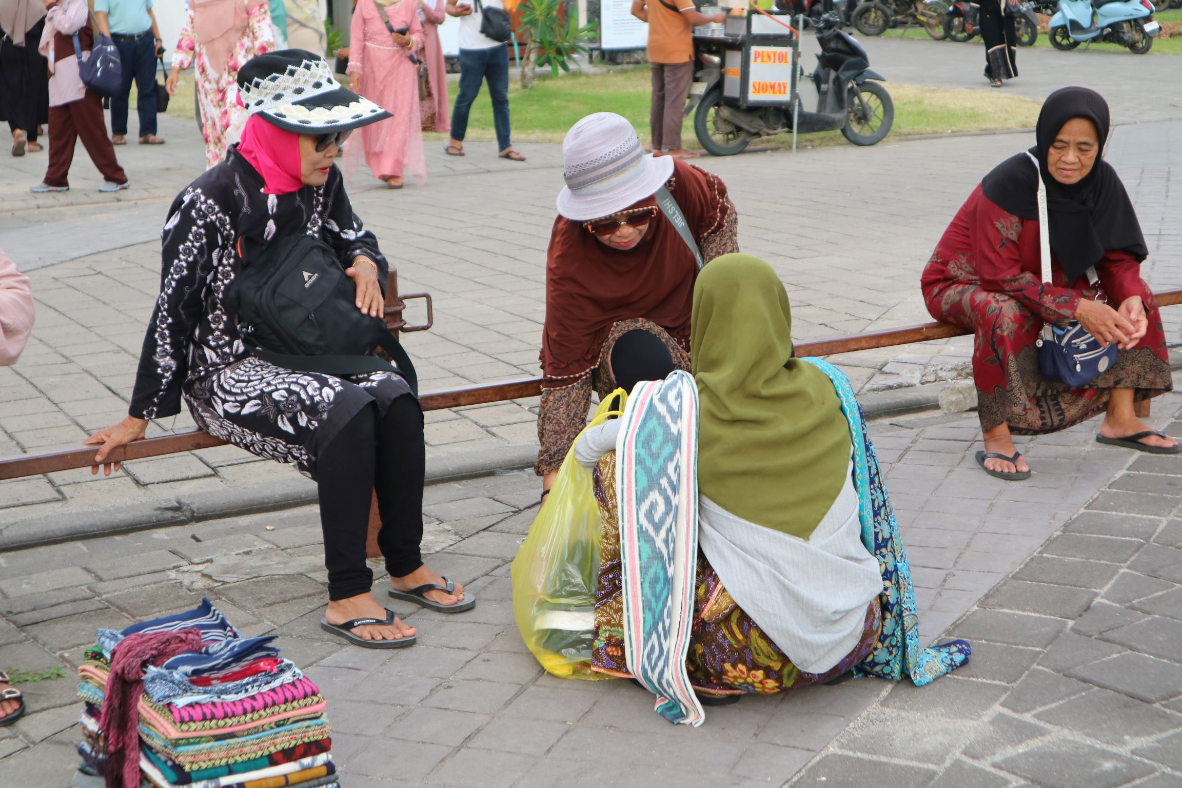 MENGAIS REJEKI: Seorang pedagang asongan kain saat menawarkan dagangannya kepada pengunjung lokal di Kuta Beach Park, The Mandalika, Loteng, Rabu (25/12).