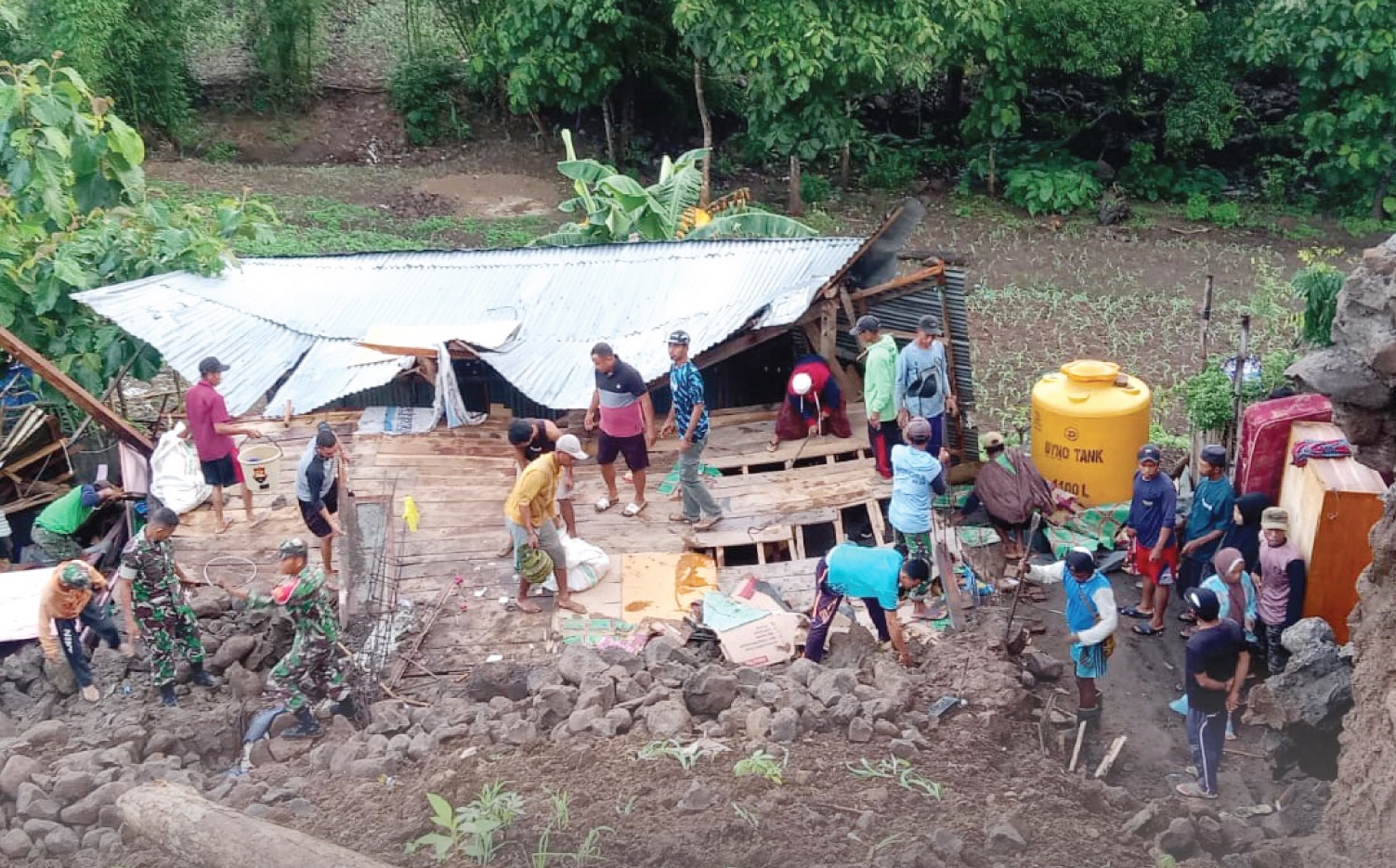 TERDAMPAK: Anggota Babinsa dibantu masyarakat setempat, mengangkut sisa-sisa barang milik seorang warga yang rumahnya terdampak banjir, di Kabupaten Bima, Sabtu (28/12).
