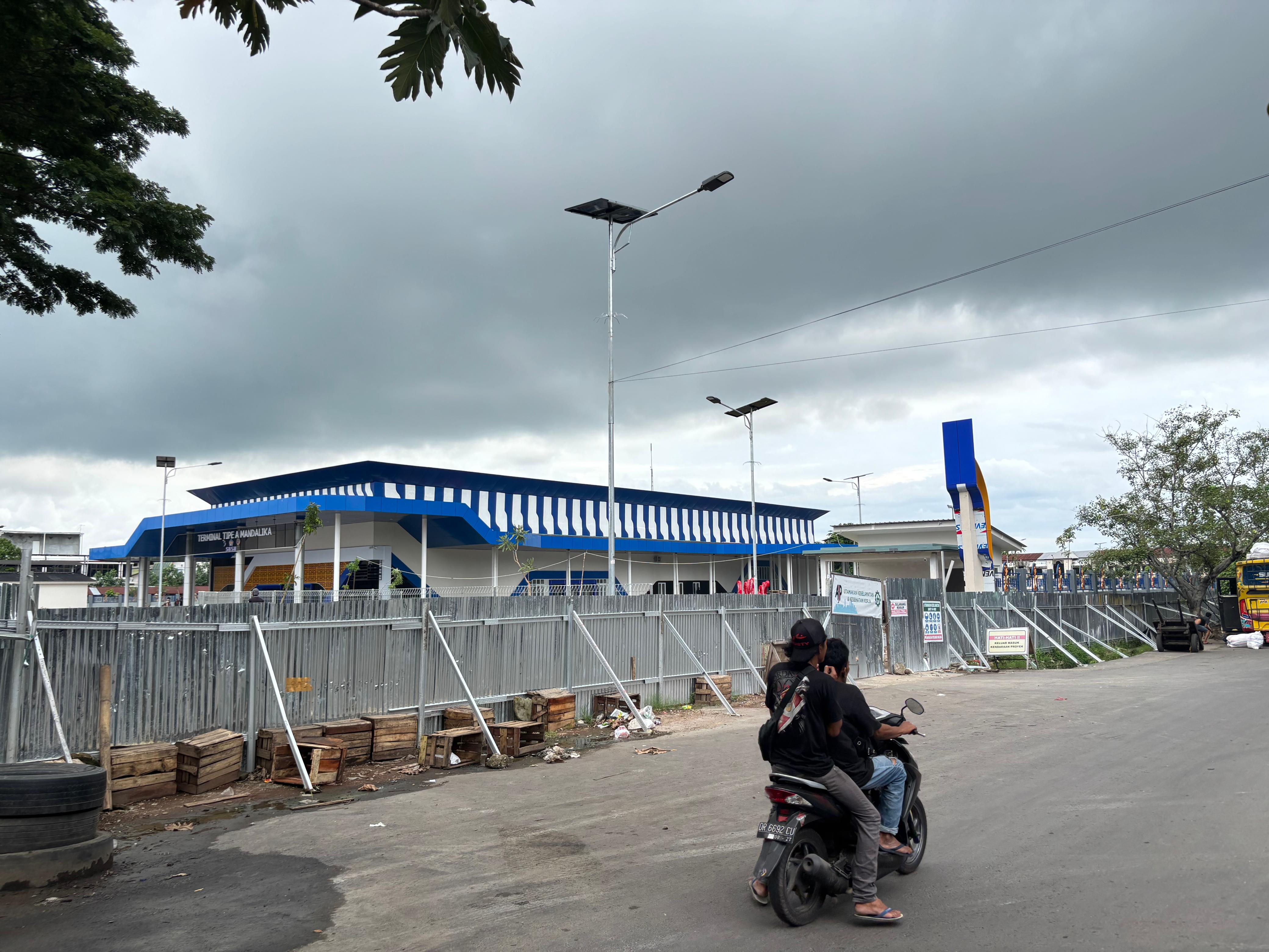 MASIH DITUTUP PAGAR: Pengendara sepeda motor melintas di depan Terminal Tipe A Mandalika, yang telah rampung dilakukan revitalisasi total oleh Kemenhub, Senin (30/12).