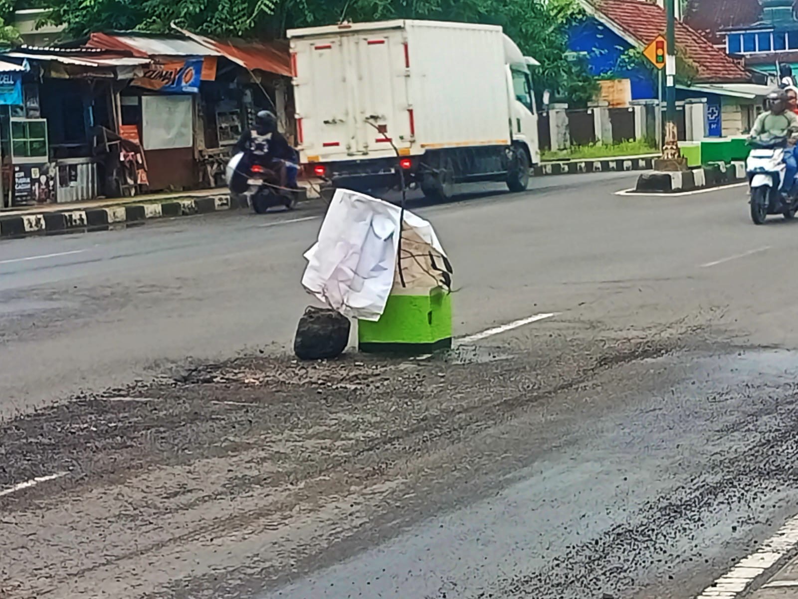 BERBAHAYA: Galian di tengah jalan TGH Faisal ditutup warga menggunakan pot bunga, Sabtu (28/12).