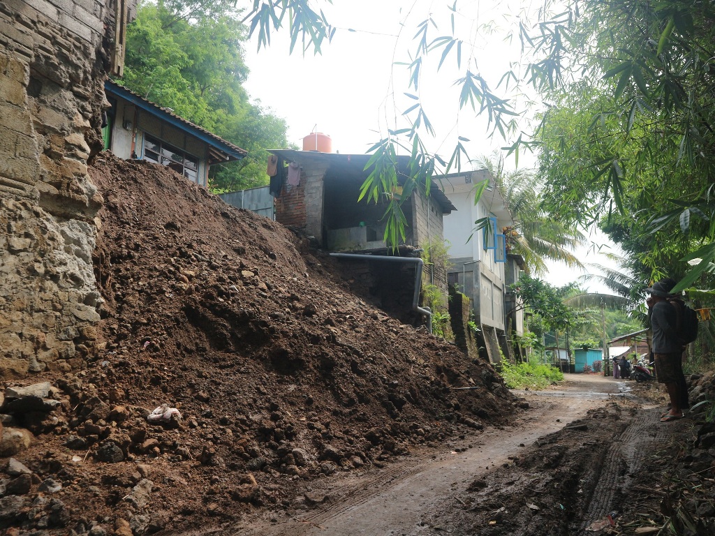LONGSOR: Saman, warga dusun Maji, Desa Pandan Duri, saat melihat kondisi depan rumahnya yang longsor akibat hujan lebat.