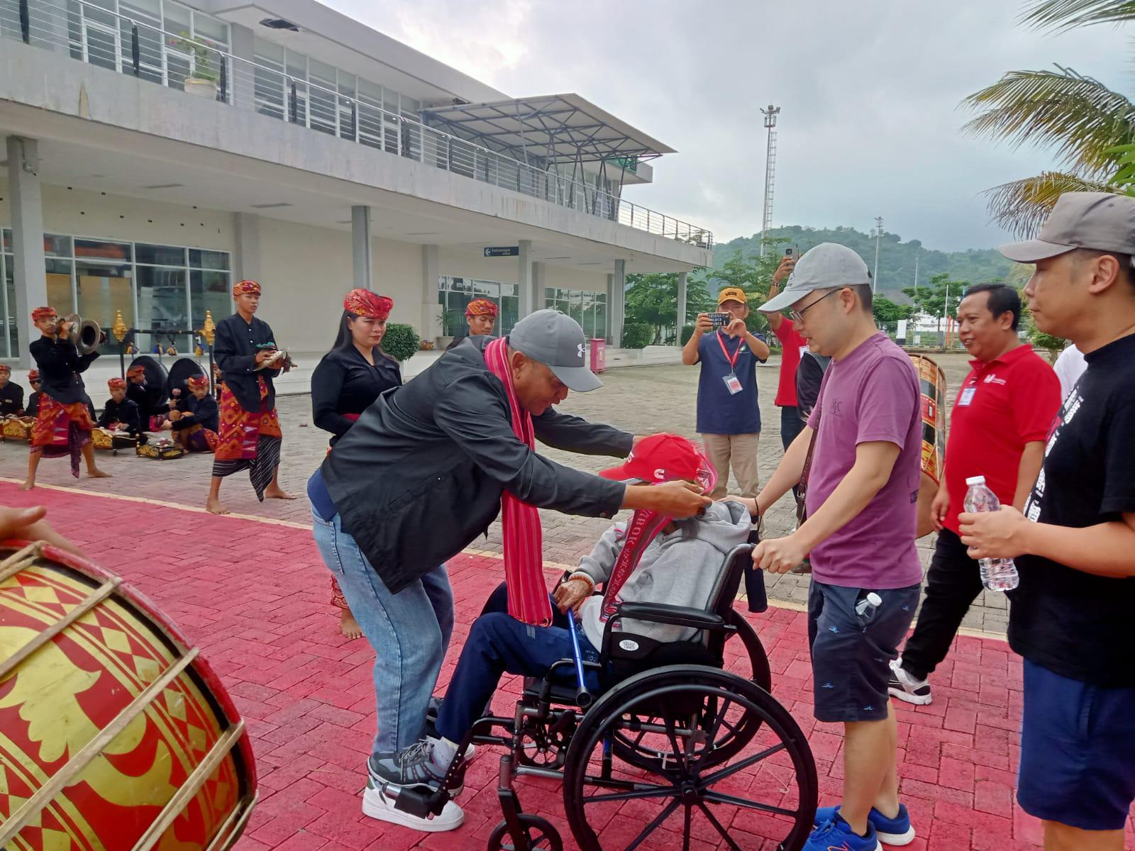 SAMBUT WISATAWAN: Ketua Badan Promosi Pariwisata Daerah (BPPD) NTB Sahlan M Saleh melakukan pengalungan selendang pada wisatawan yang turun dari Kapal pesiar Celebrity X Cruise di Gili Mas Lembar.